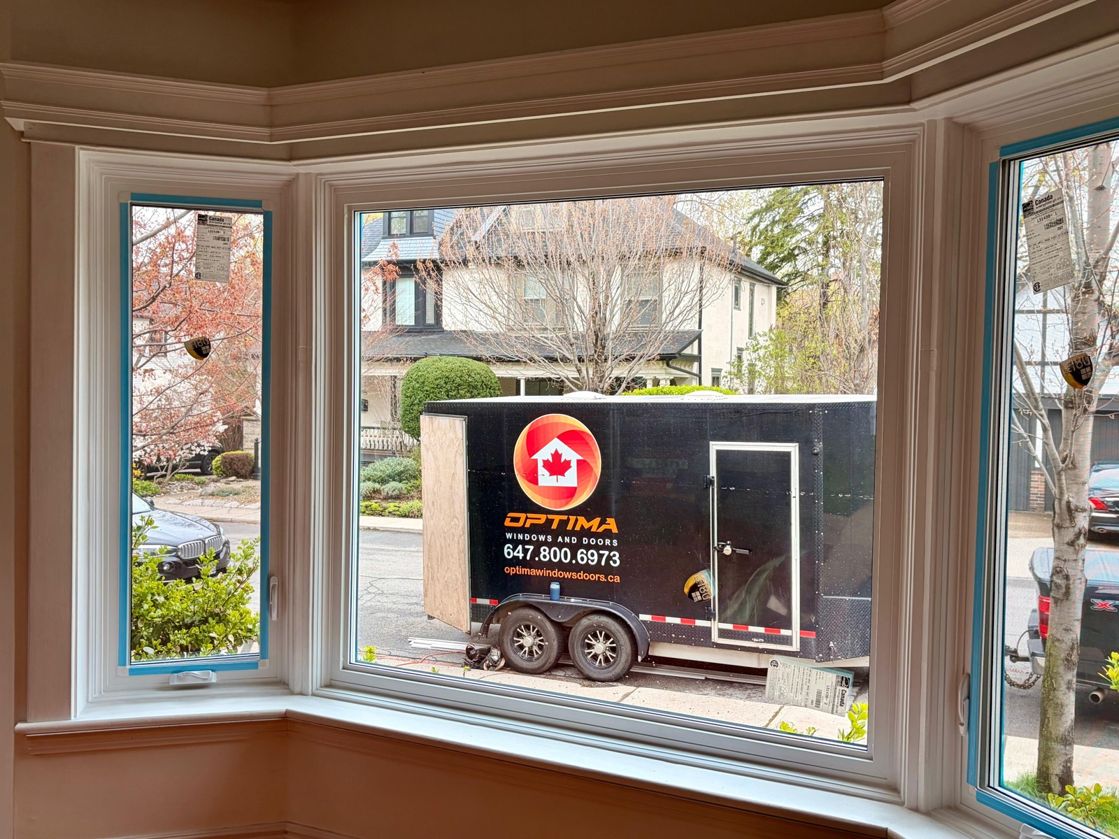 Bay window replacement seen from inside, with the Optima installation trailer parked outside installed by Optima Windows and Doors in the Greater Toronto Area