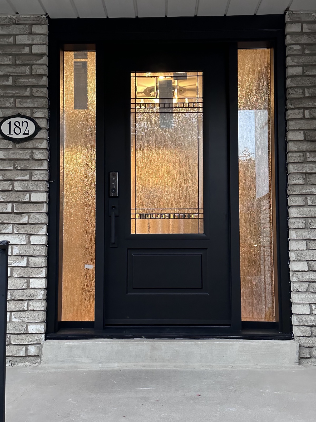 Black entry door with a frosted glass panel installed by Optima Windows and Doors in the Greater Toronto Area