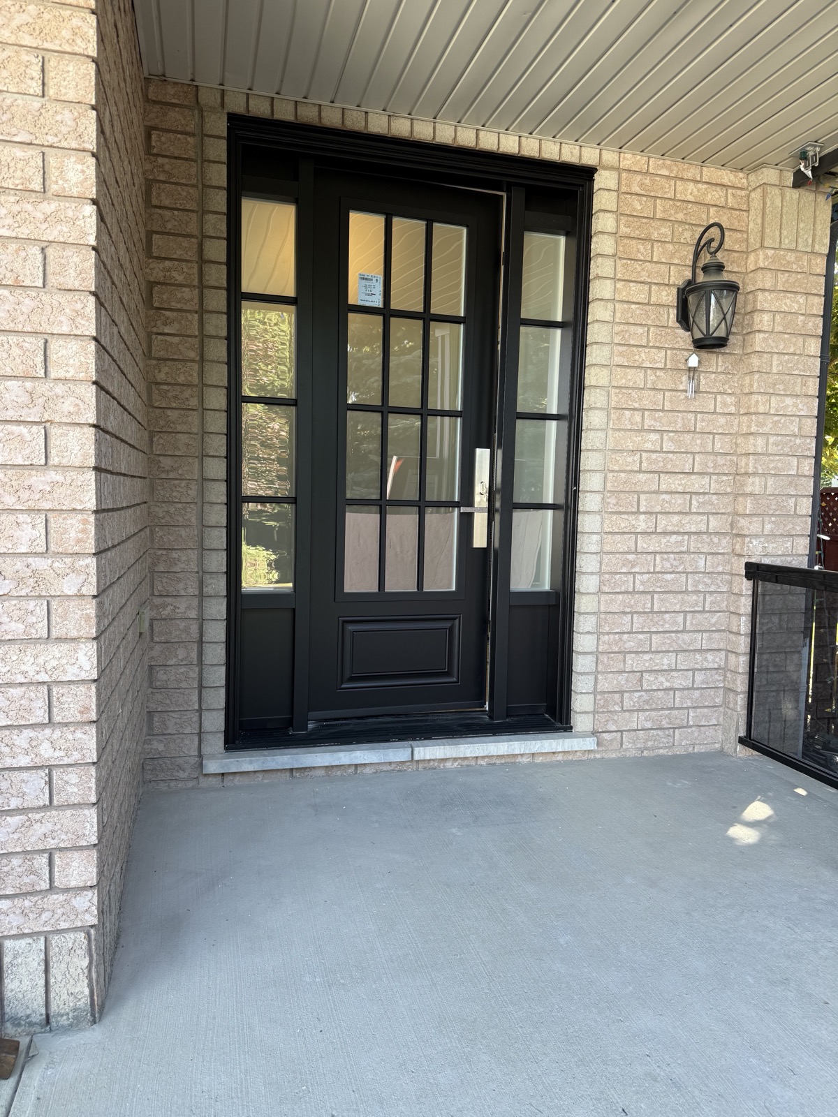Black entry door with glass sidelites on a brick home installed by Optima Windows and Doors in the Greater Toronto Area