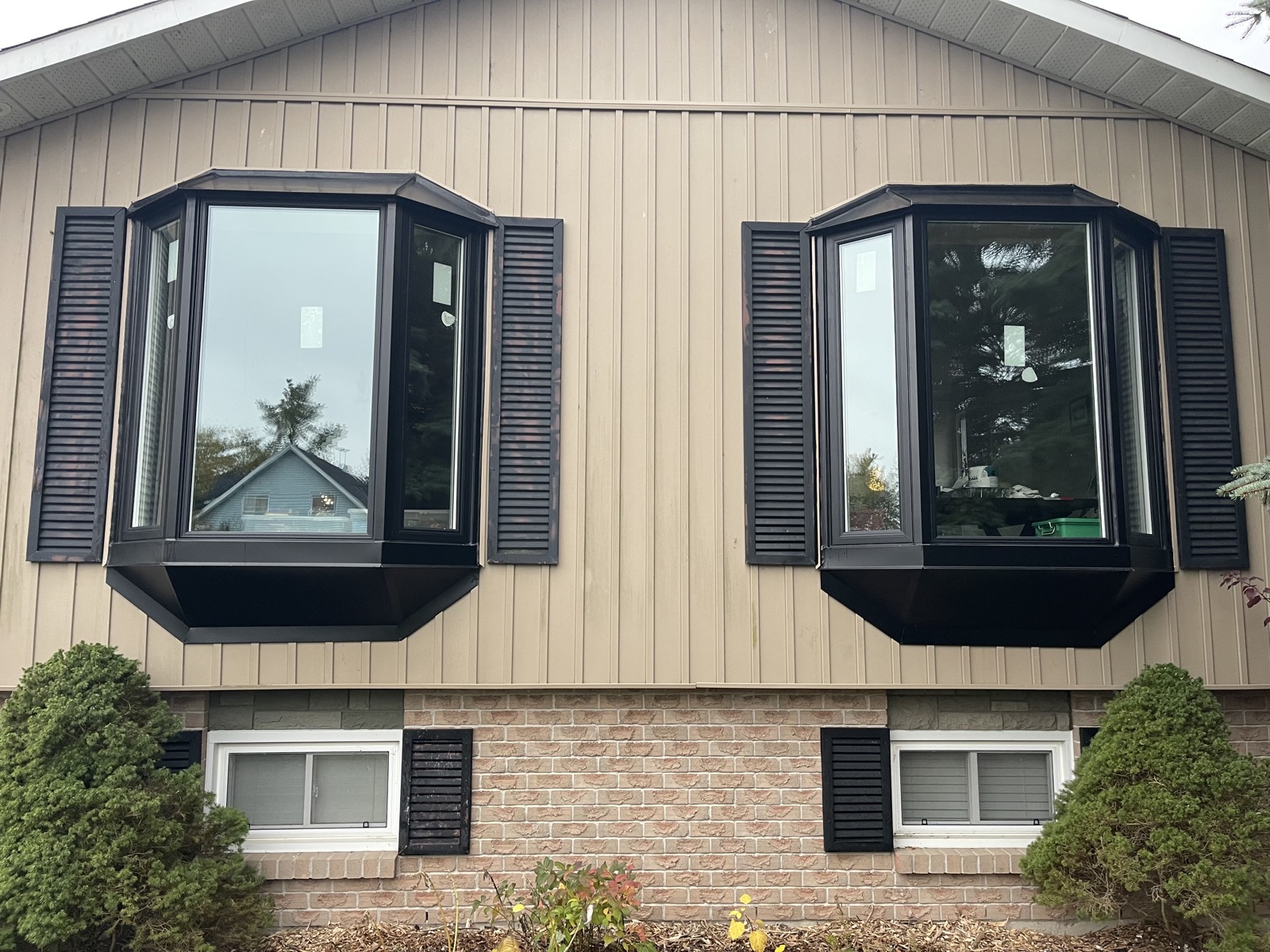 Black framed bay windows on a siding clad home installed by Optima Windows and Doors in the Greater Toronto Area