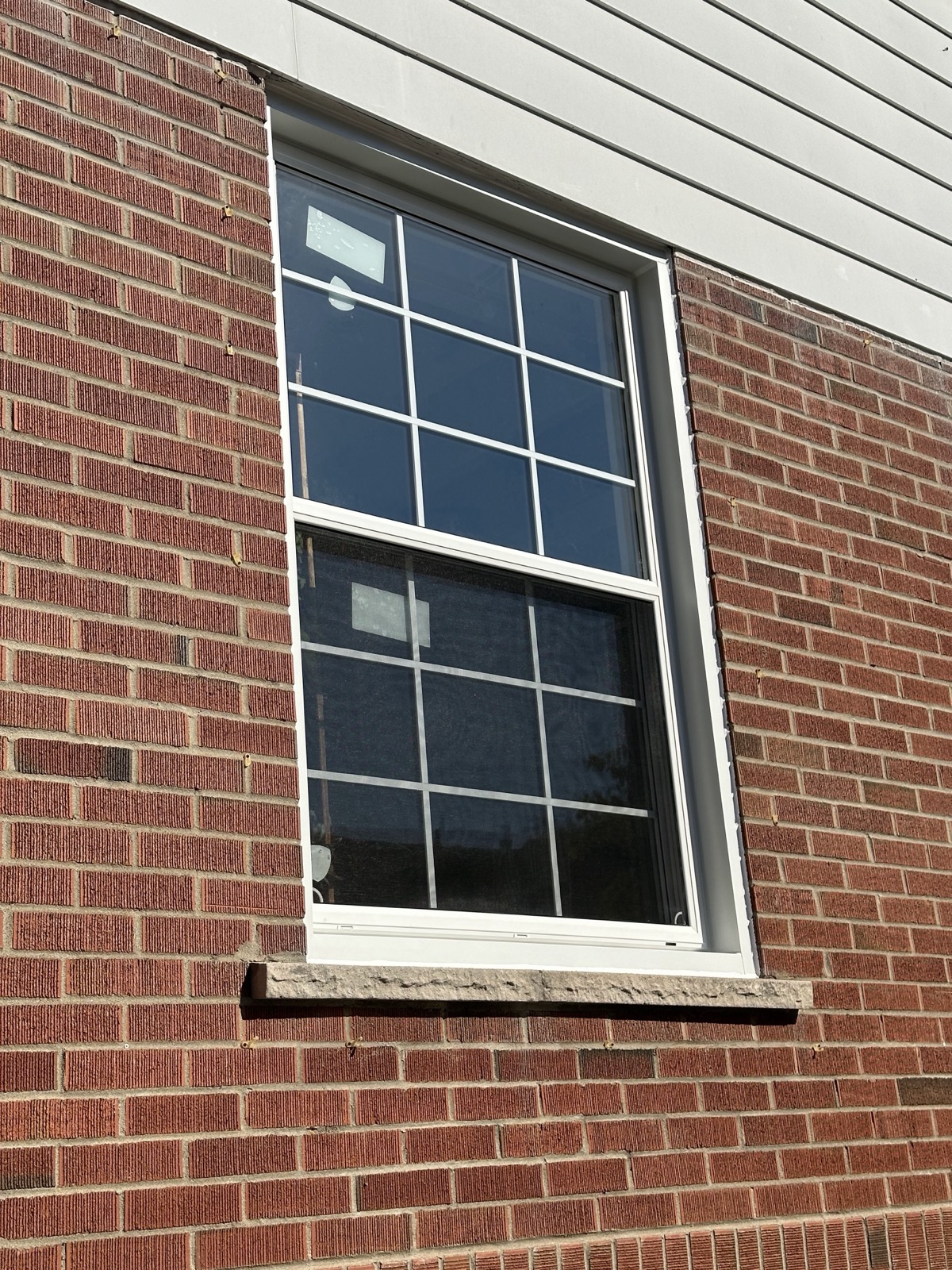 Black framed window with colonial grid on grey siding installed by Optima Windows and Doors in the Greater Toronto Area