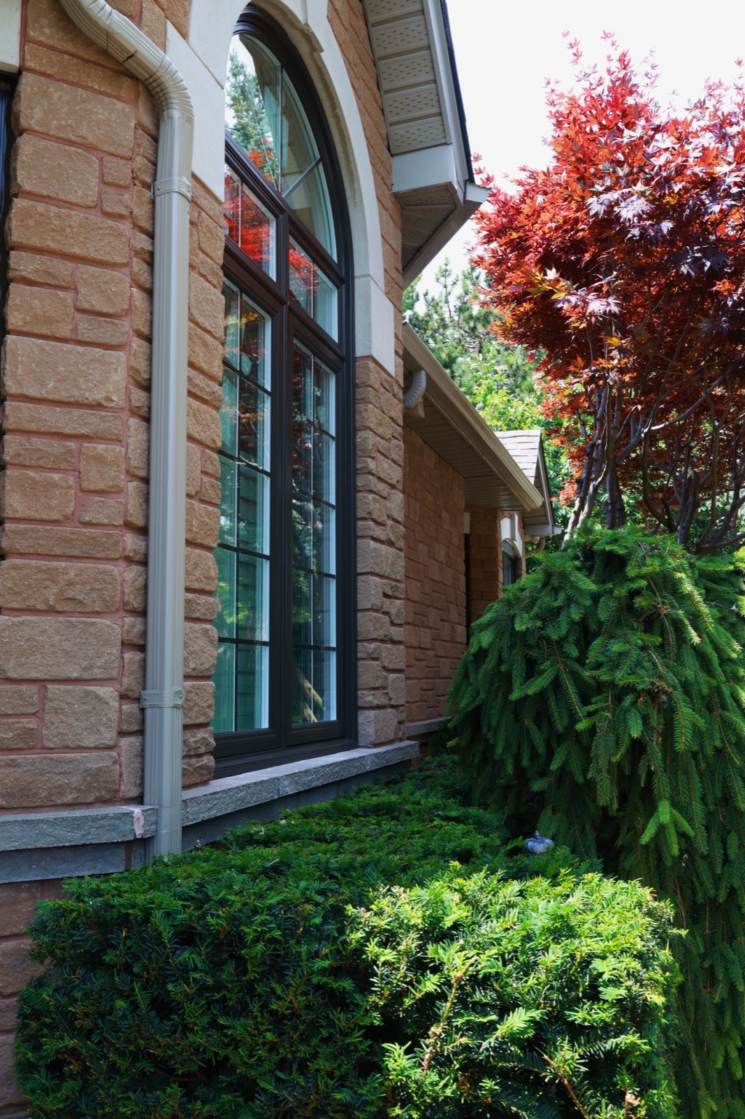 Black framed windows on a stone home installed by Optima Windows and Doors in the Greater Toronto Area