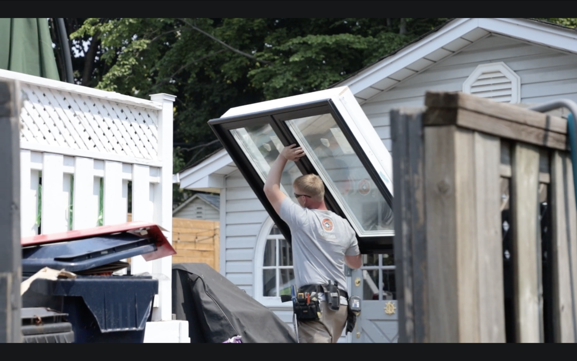 An installer carrying a large window outside a home