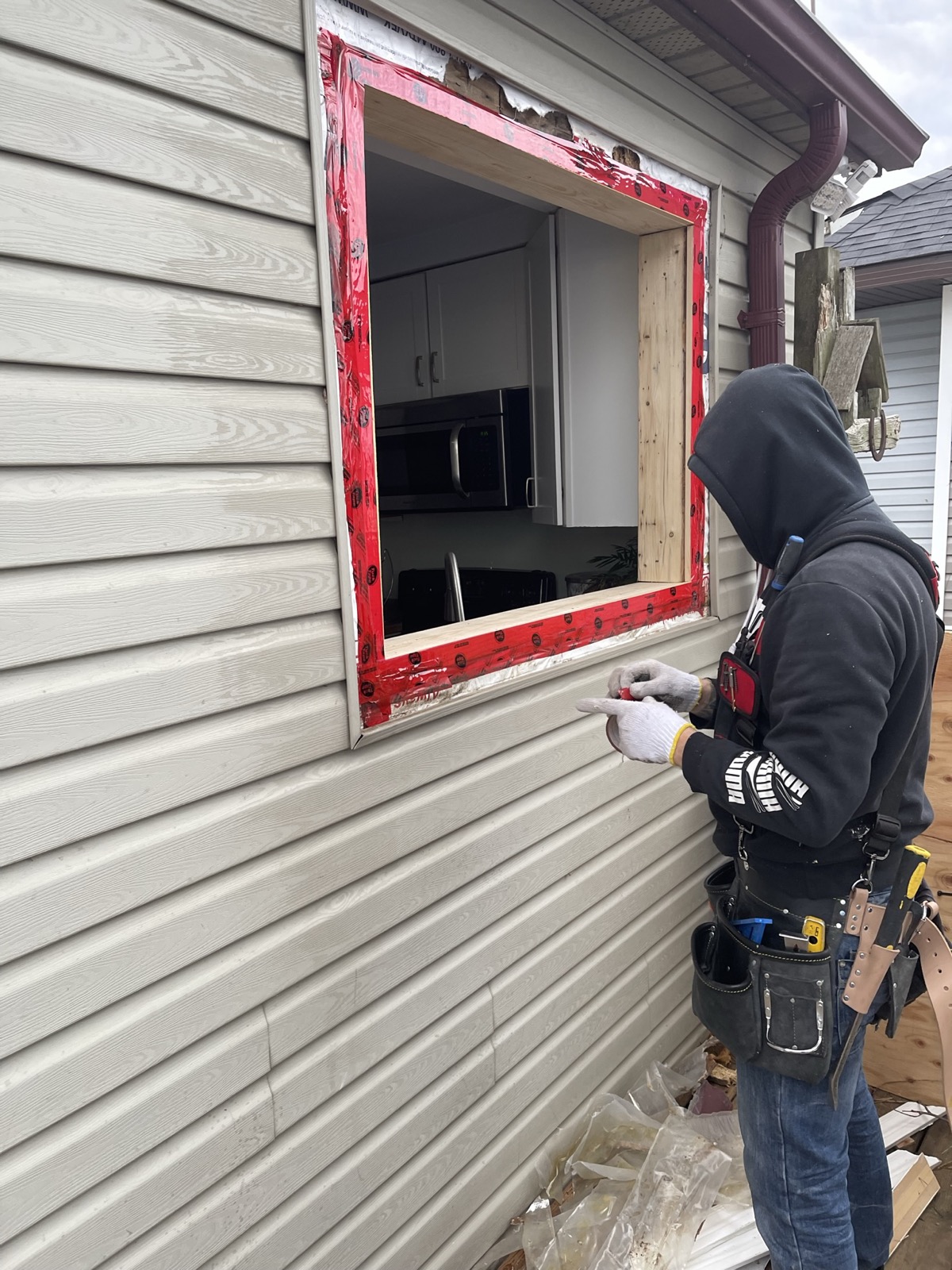 Optima installer fitting a new window on a siding clad home installed by Optima Windows and Doors in the Greater Toronto Area