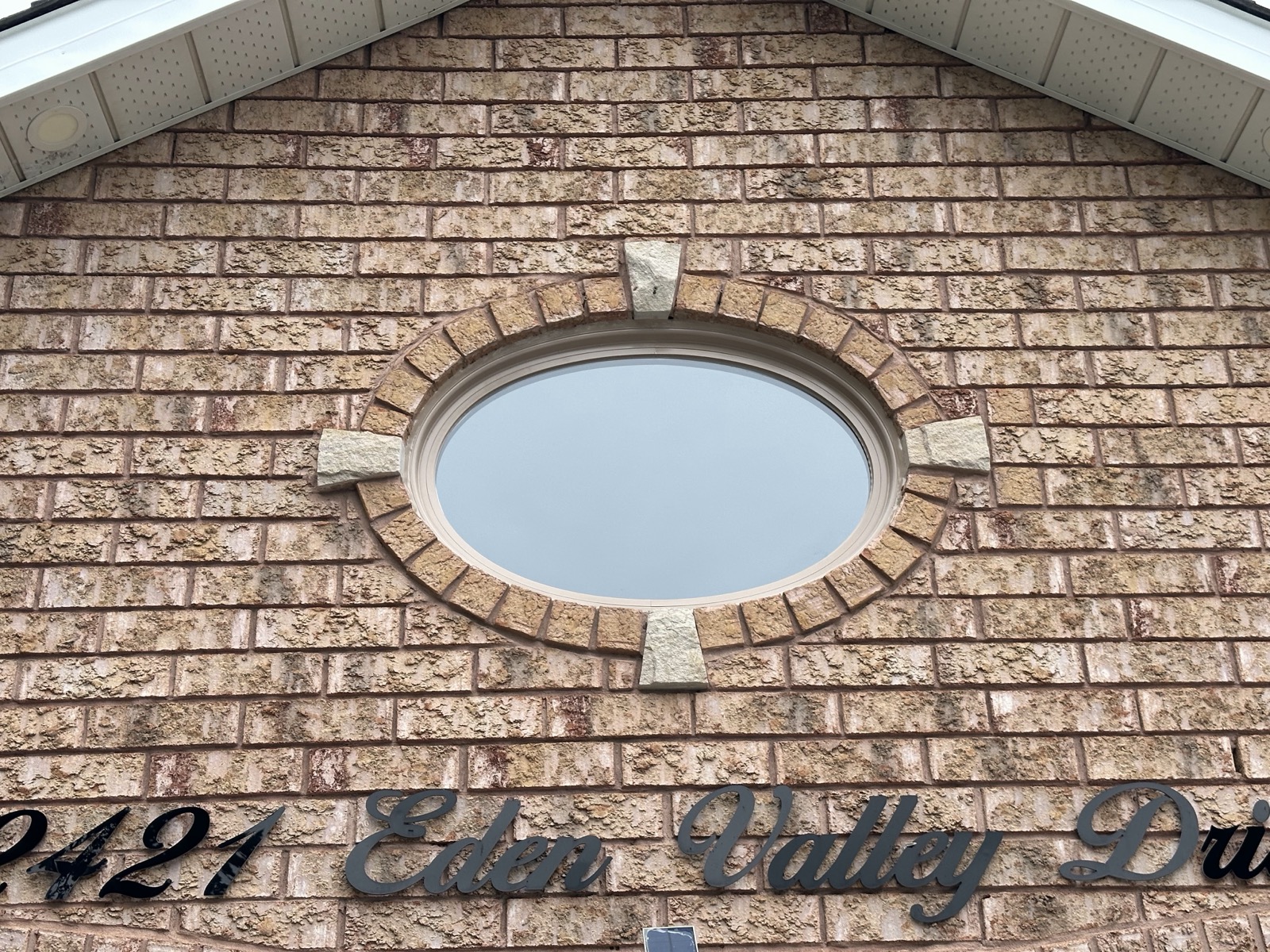 Oval accent window set into a brick facade installed by Optima Windows and Doors in the Greater Toronto Area