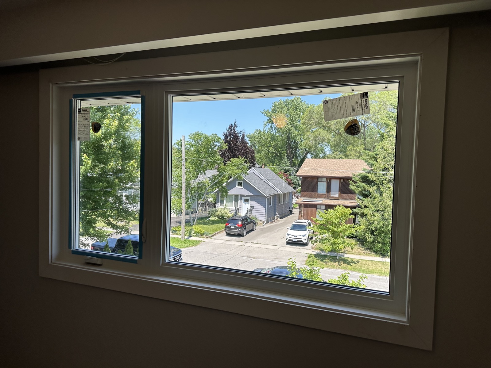 Picture window reflecting the street on a brick home installed by Optima Windows and Doors in the Greater Toronto Area