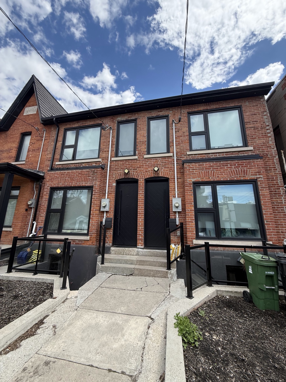 Red brick semi detached home with new black windows and entry doors installed by Optima Windows and Doors in the Greater Toronto Area