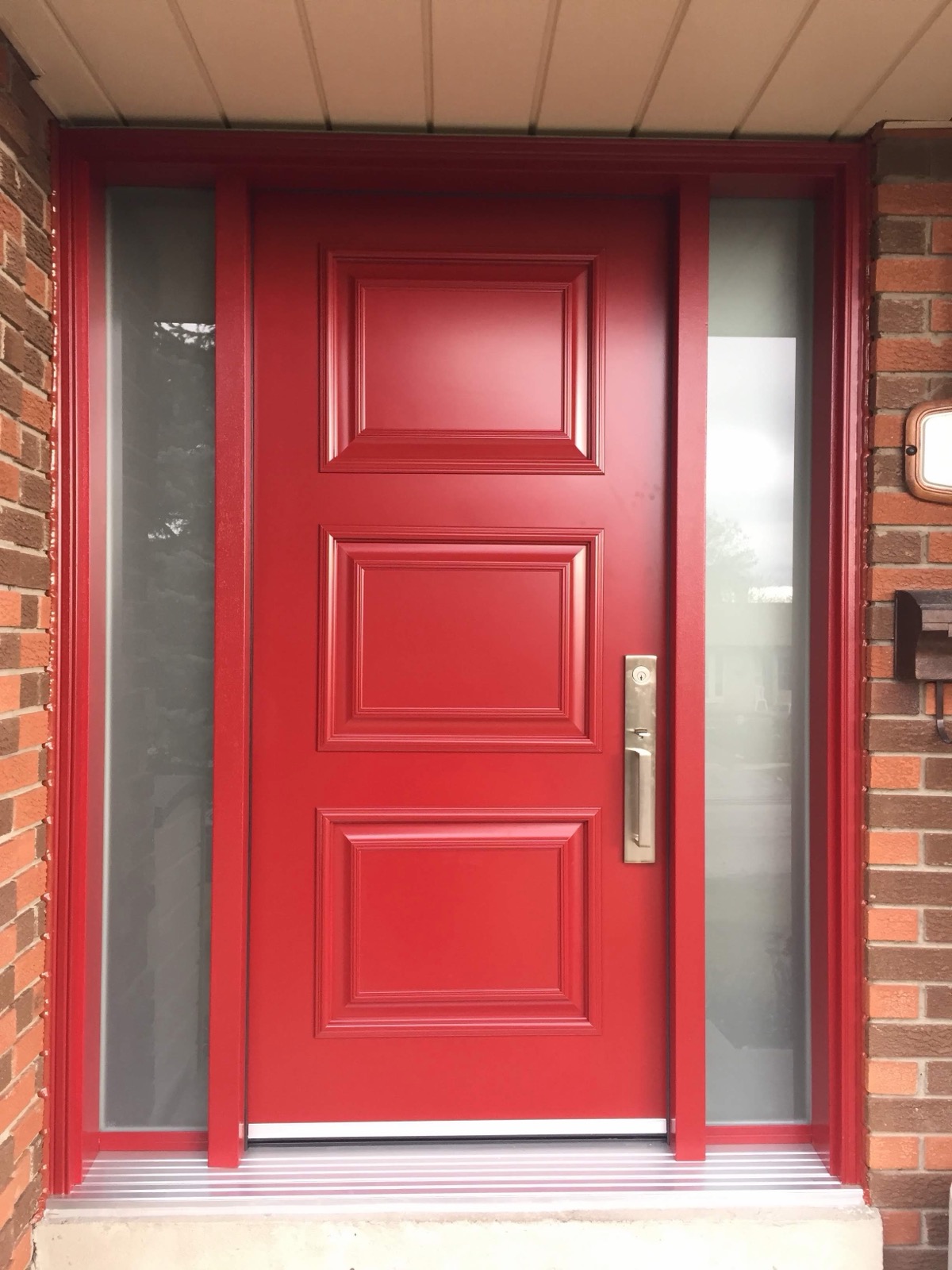 Red entry door with brushed hardware installed by Optima Windows and Doors in the Greater Toronto Area