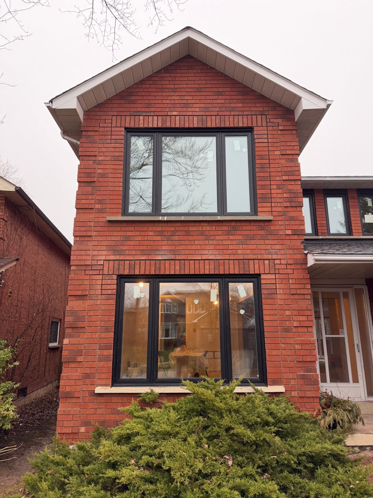 Three storey red brick home with black replacement windows installed by Optima Windows and Doors in the Greater Toronto Area