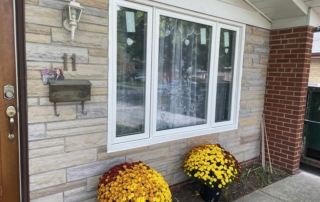 White bay window on a home with autumn flowers installed by Optima Windows and Doors in the Greater Toronto Area