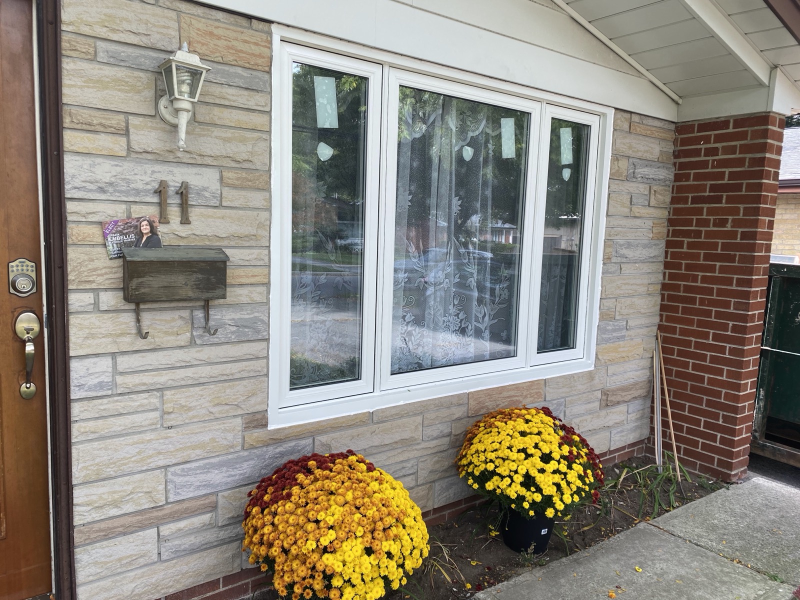 White bay window on a home with autumn flowers installed by Optima Windows and Doors in the Greater Toronto Area
